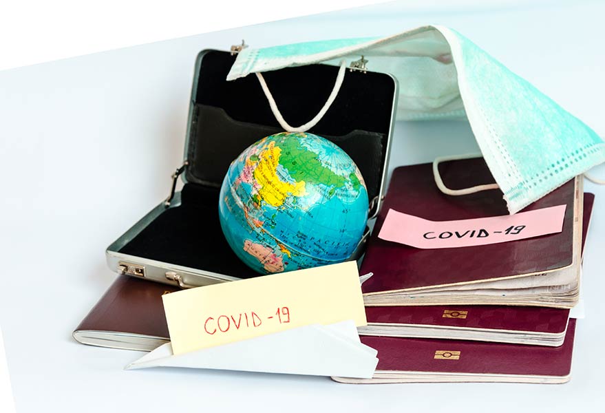 Miniature globe in a small brief case, masks, passports with COVID-19 notes